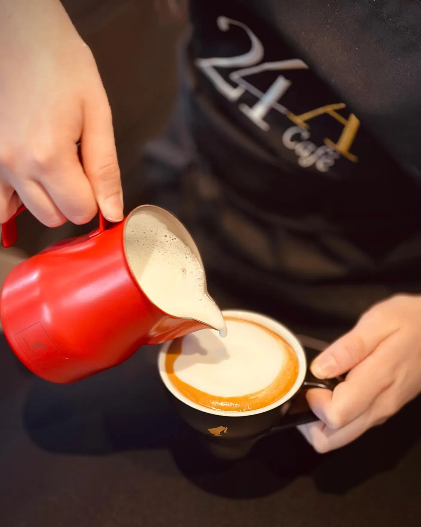 Latte Art wird mit roter Kanne eingeschenkt